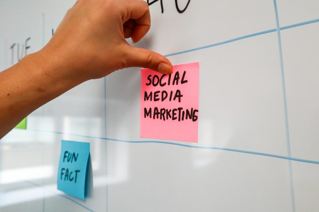 Person sticking a post-it on a white board with the words Social Media Marketing written on it